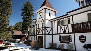 A traditional Tudor-style building with a prominent tower and clock, surrounded by snow-covered ground and trees. - Fawn Valley Inn: 253 1 Bedroom Apts (Estes Park)
