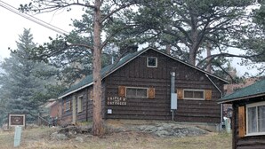 En rustik træbygning med skilten "TRIPLE R COTTAGES", med et simpelt, udekoreret ydre og et skråt tag.