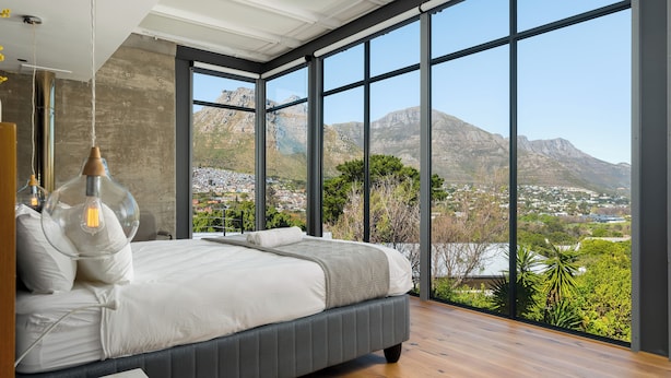 Ein modernes Schlafzimmer mit einem großen Bett, Bergblick und Holzboden.