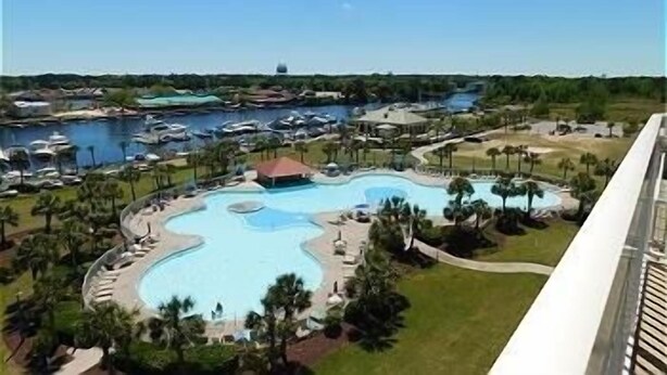 Un resort con una piscina central grande, varias piscinas más pequeñas y un puerto deportivo con barcos.