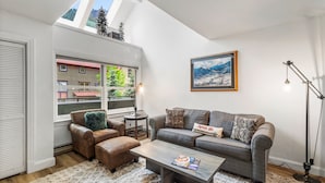 A living room with a sofa, armchair, coffee table, and a painting on the wall.