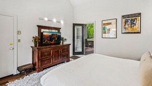 A bedroom with a bed, dresser, and artwork on the wall.