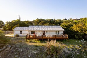 A single-story house with a metal roof, a wooden deck, and a front porch.
