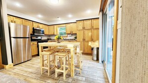 A kitchen with wooden cabinets, a stainless steel refrigerator, a microwave, and a wooden dining table with benches. - Cozy cabin on 5 acres of wooded land! (Wausaukee)