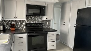 Una cucina con mobili bianchi, un piano cottura nero e un frigorifero nero.