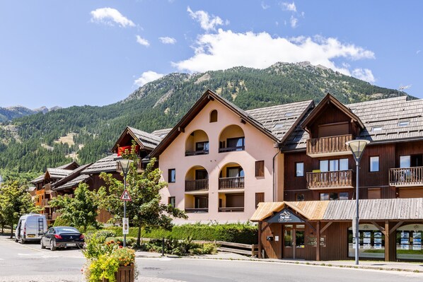 A mountain lodge with multiple balconies and a mountain backdrop.