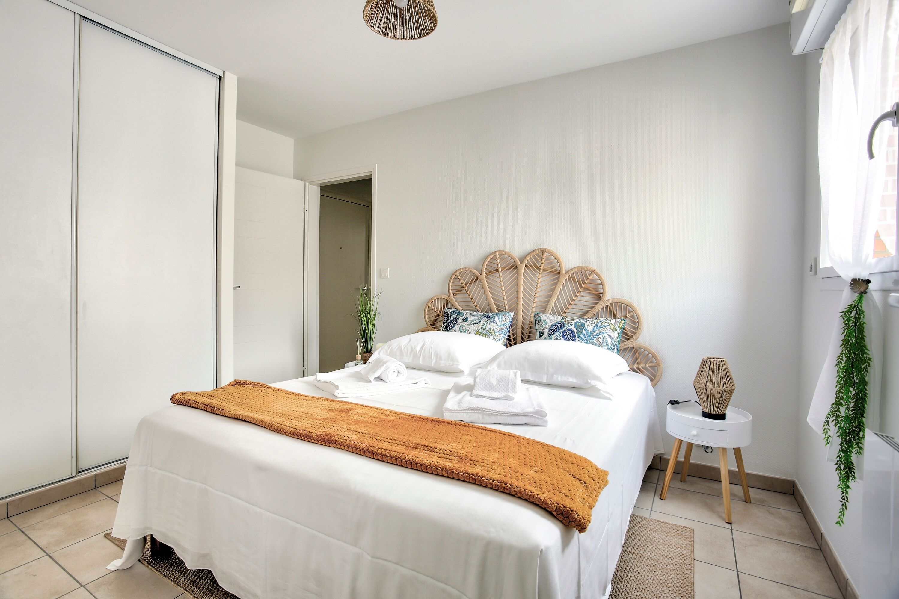 Une chambre à coucher avec un lit, une table de chevet, une plante suspendue et une armoire.