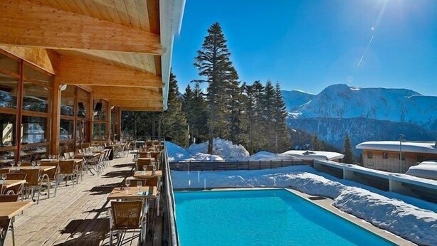 A poolside area with outdoor seating, a pool, and a mountain view. - Le Silène - Appt pour 6 (Chamrousse)