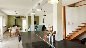 A modern kitchen with a large island, pendant lights, and a staircase. - La Bergerie du Pré de l'Orme - Avec vue montagne (La Bresse)