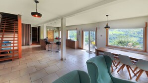 A spacious living area with a large window, a dining table, and a staircase. - La Bergerie du Pré de l'Orme - Avec vue montagne (La Bresse)