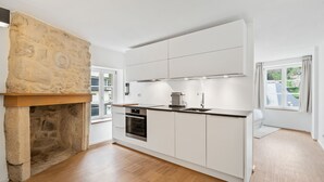 A modern kitchen with white cabinetry, a built-in oven, and a stone fireplace. - Modern Apt Old Town w Panoramic View ID4 (Luxembourg City)
