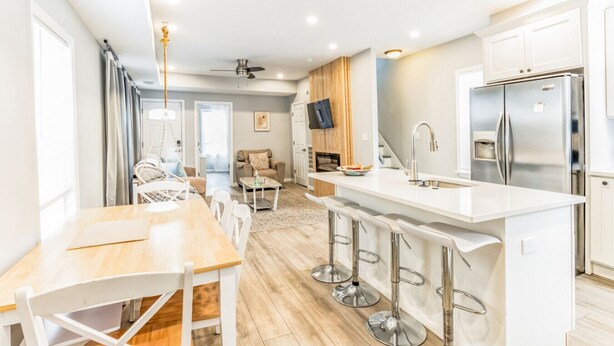 A modern kitchen with a central island, bar stools, and a built-in TV.