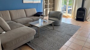 Ein Wohnzimmer mit einer Couch, einem Sessel, einem Couchtisch und einem Bücherregal.