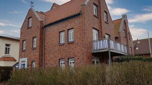 Ein großes Backsteingebäude mit Balkon, zahlreichen Fenstern und einem Schornstein.