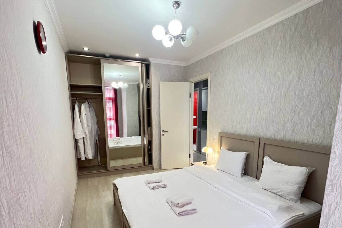 Une chambre d’hôtel moderne dotée d’un grand lit, d’un dressing et d’une salle de bain visible à travers une porte ouverte.