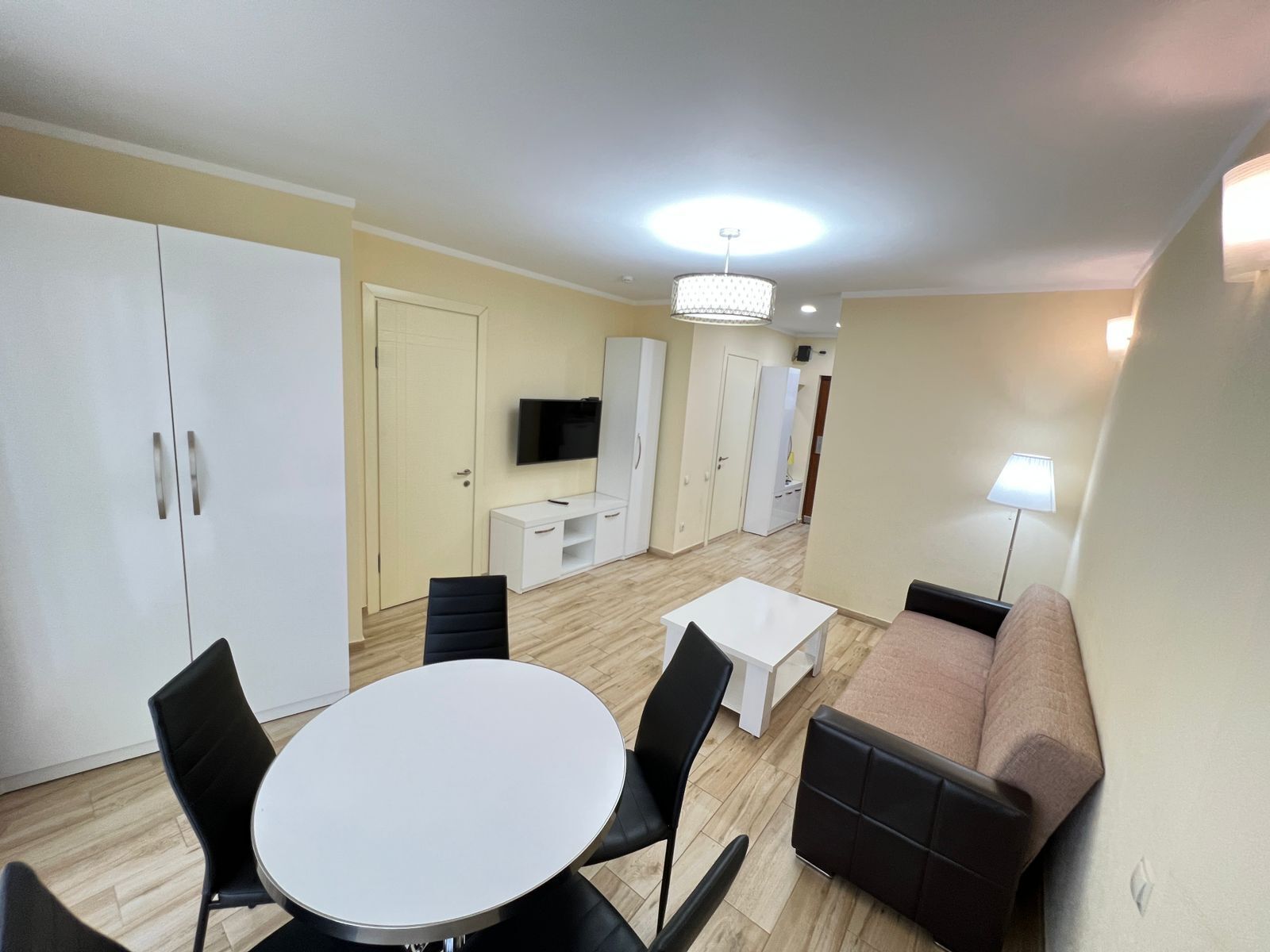 Un espace de vie compact comprenant une table à manger, des chaises, un canapé, un téléviseur et une lampe.