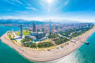 Vista aérea de una ciudad costera con un complejo moderno destacado, una playa y una masa de agua.