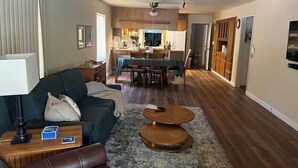A living room with a sofa, coffee table, and a dining area with chairs and a table.