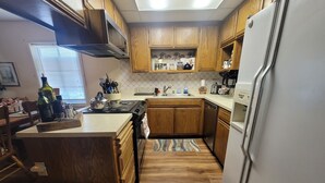 A kitchen with wooden cabinets, a stove, a sink, and a refrigerator.