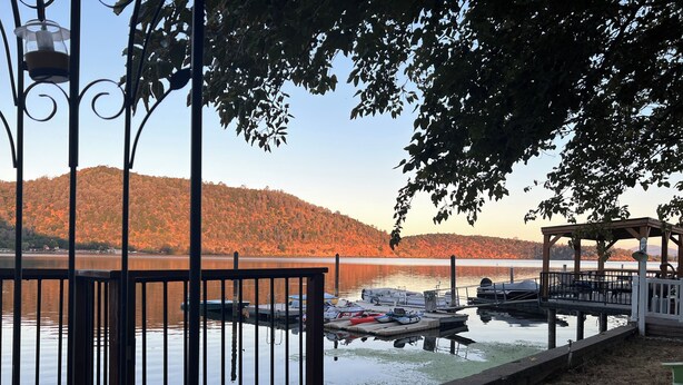 A wooden deck with a railing, docked boats, and a gazebo.