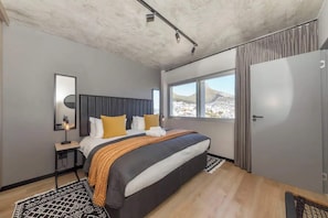 Un dormitorio moderno con una cama grande, una mesita de noche, una ventana con vistas y un armario.