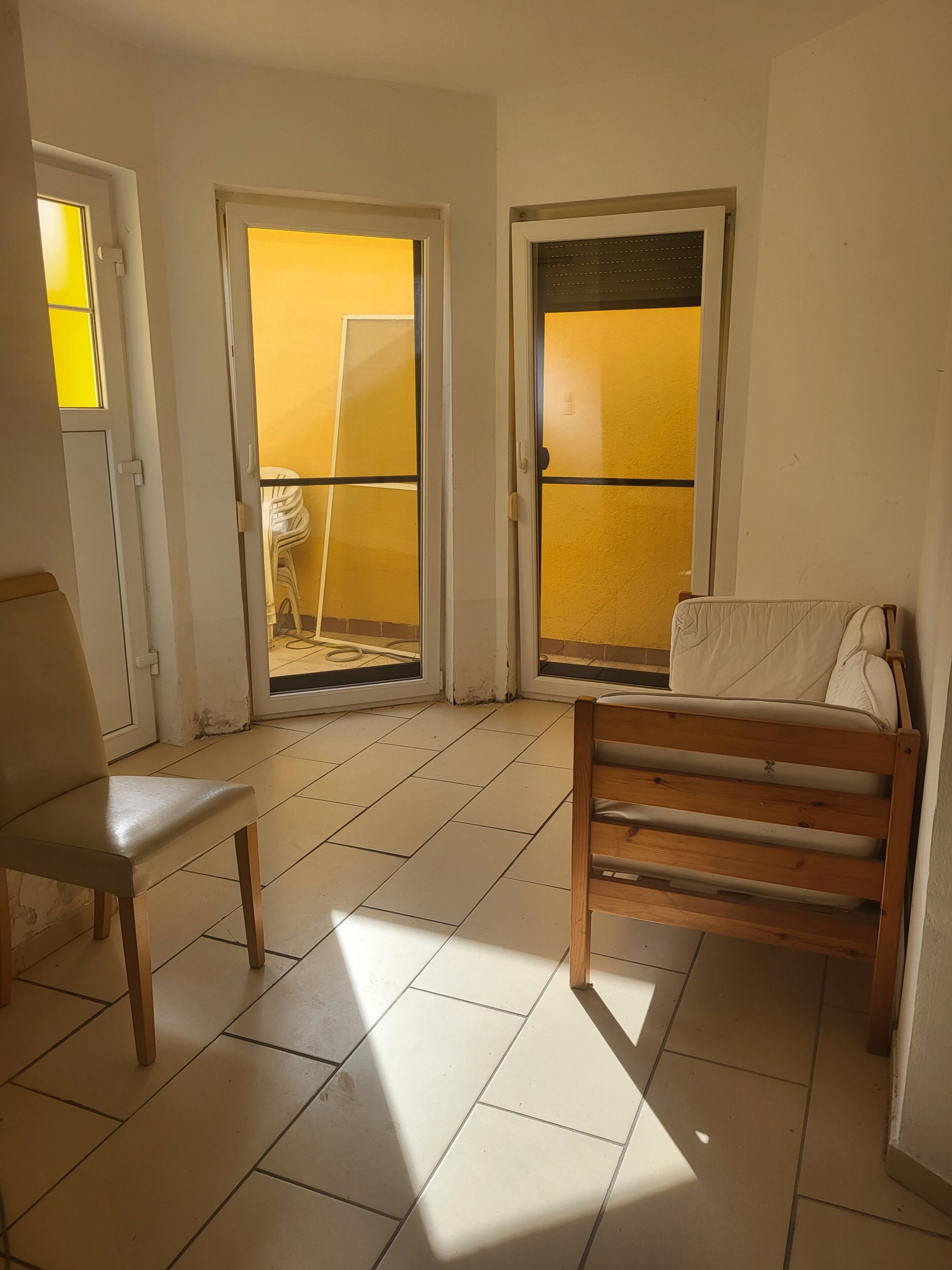 A room with a bench, a chair, and two doors leading to an outdoor area.