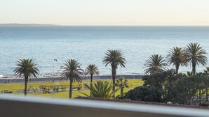 A coastal view with palm trees, a playground, and a distant city skyline. - Six on N 302 (Cape Town)