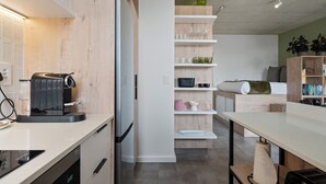 A modern kitchen with a built-in coffee machine, a refrigerator, and a microwave on a white countertop. - Six on N 302 (Cape Town)