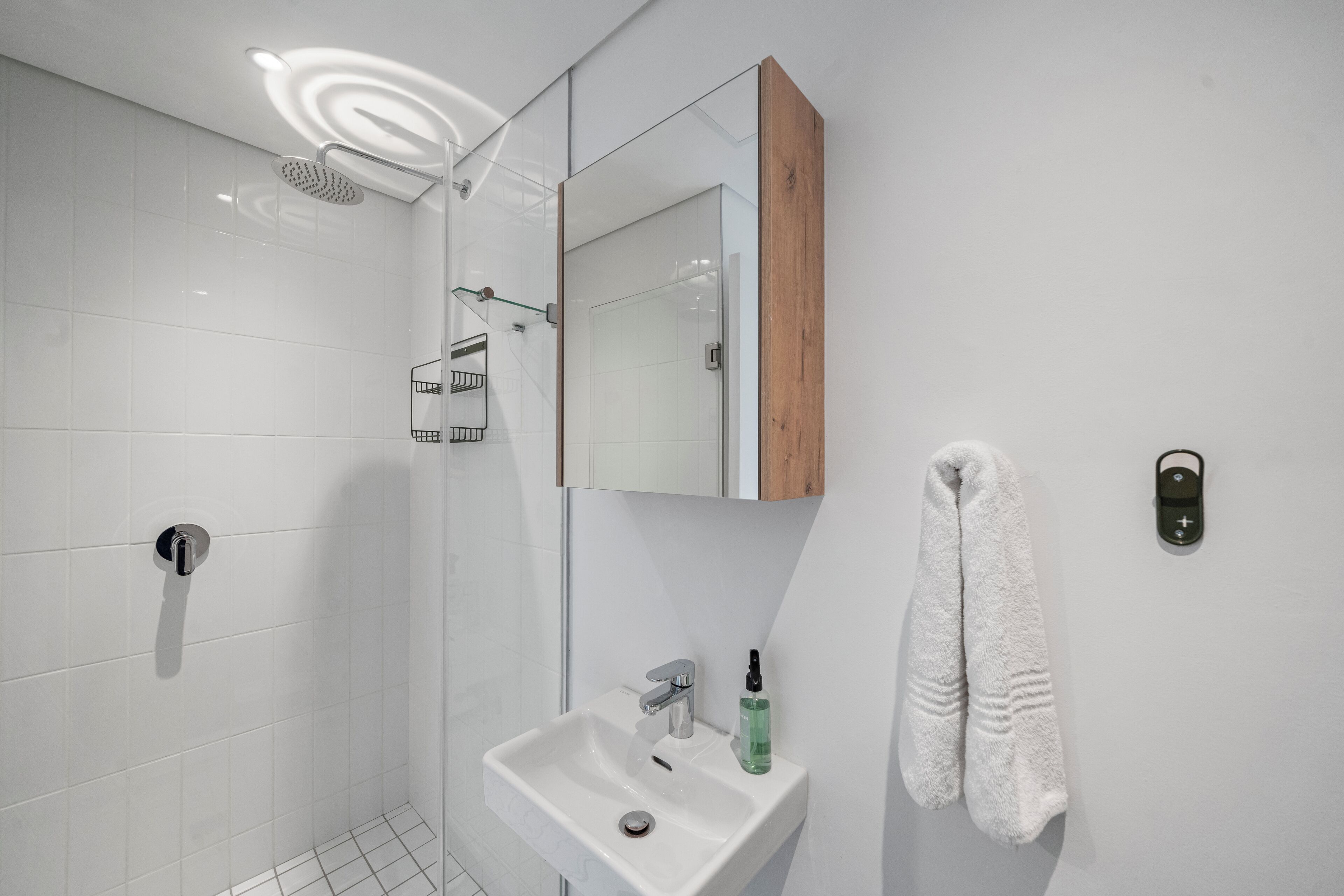 Un baño moderno con ducha, lavabo y toallero.