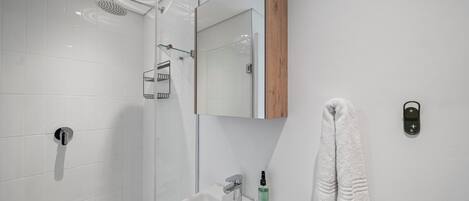 Un baño moderno con ducha, lavabo y toallero.