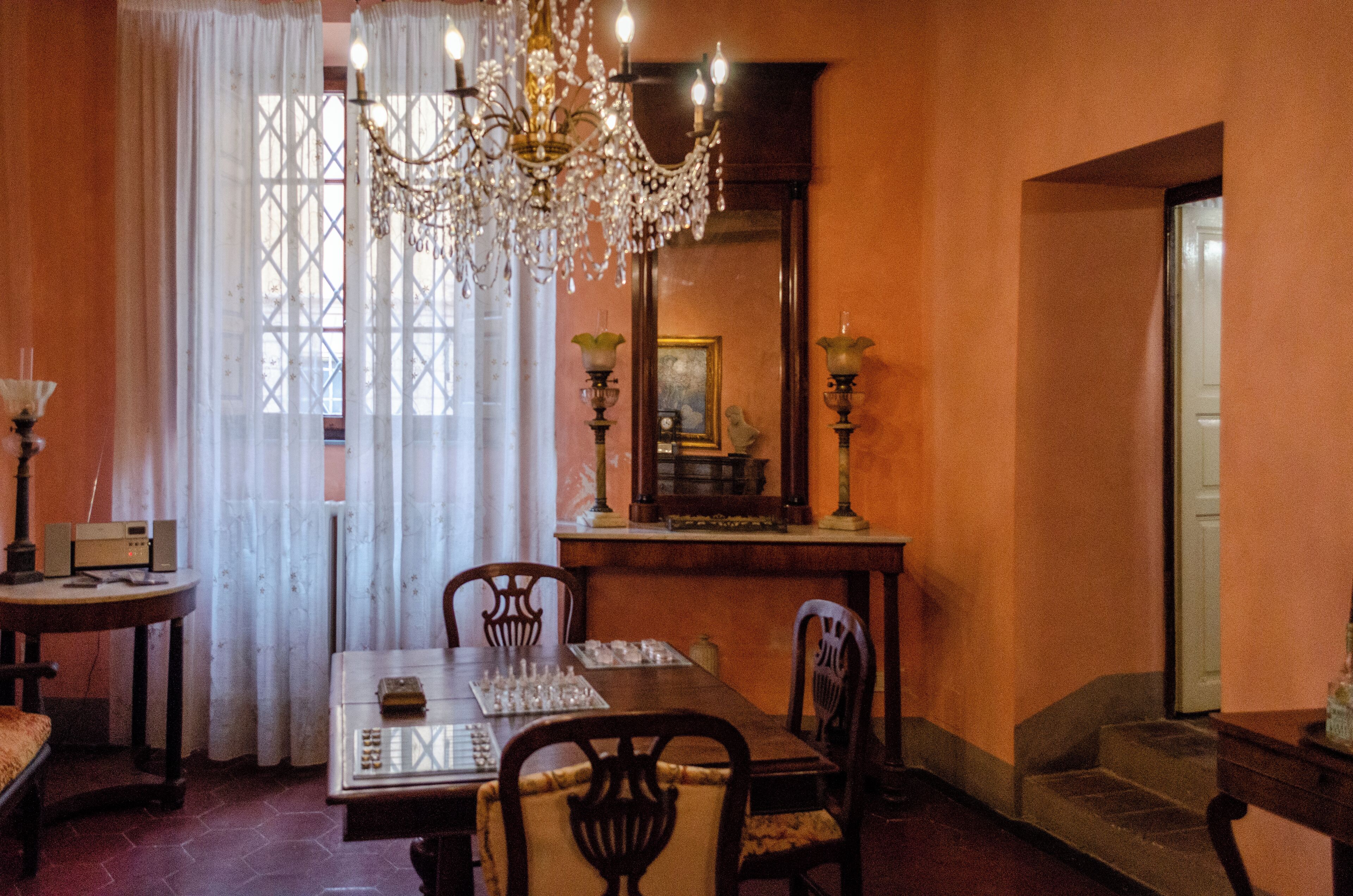 A dining room with a chandelier, a table set for four, and a mirror on the wall.