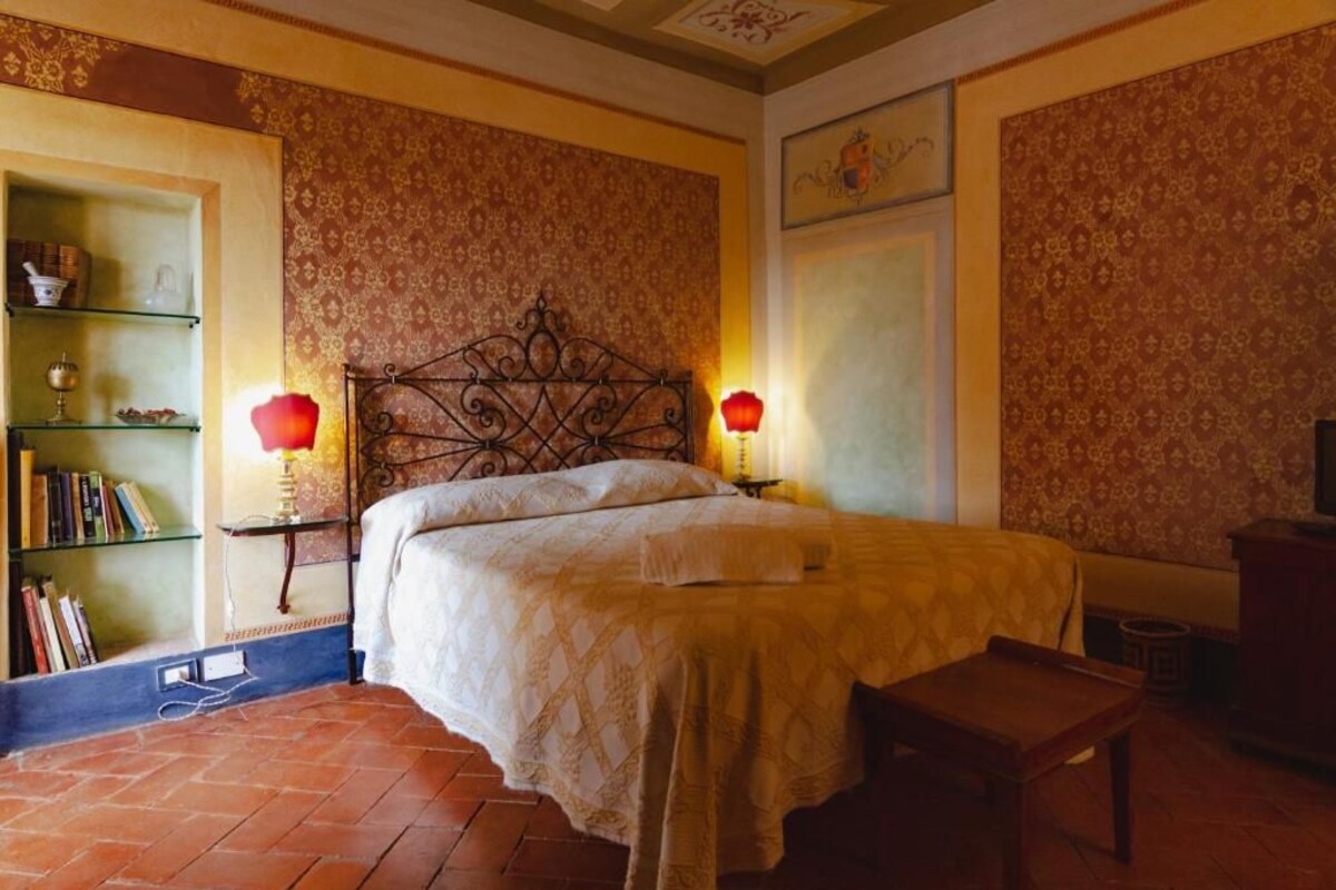 A bedroom with a bed, two bedside tables, a bookshelf, and a bench.