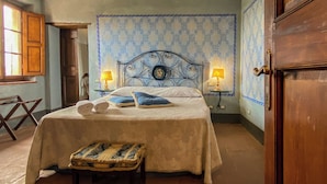 A bedroom with a bed, two bedside lamps, a wooden bench, and a patterned wall.