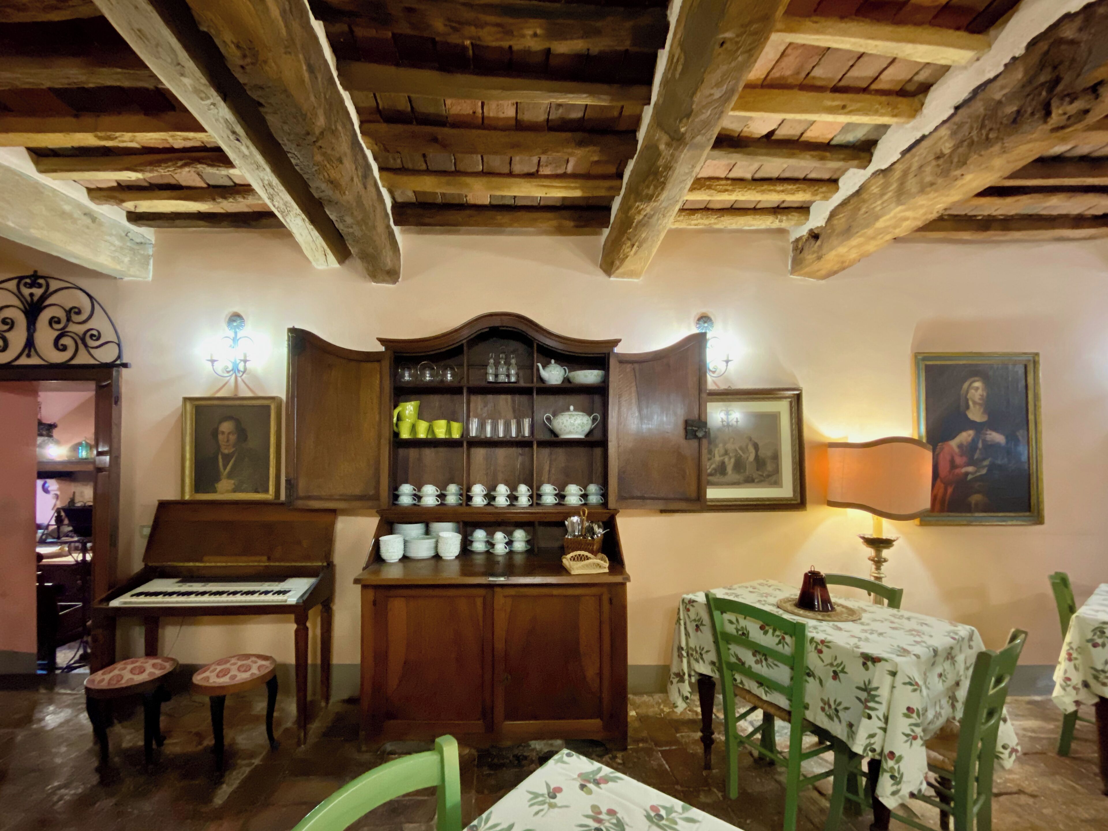 Una habitación acogedora con un armario de madera, un piano y una mesa con sillas.