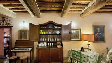 Una habitación acogedora con un armario de madera, un piano y una mesa con sillas.