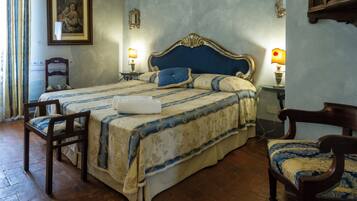 A traditional bedroom with a large bed, two bedside tables, a chair, and a wooden headboard.