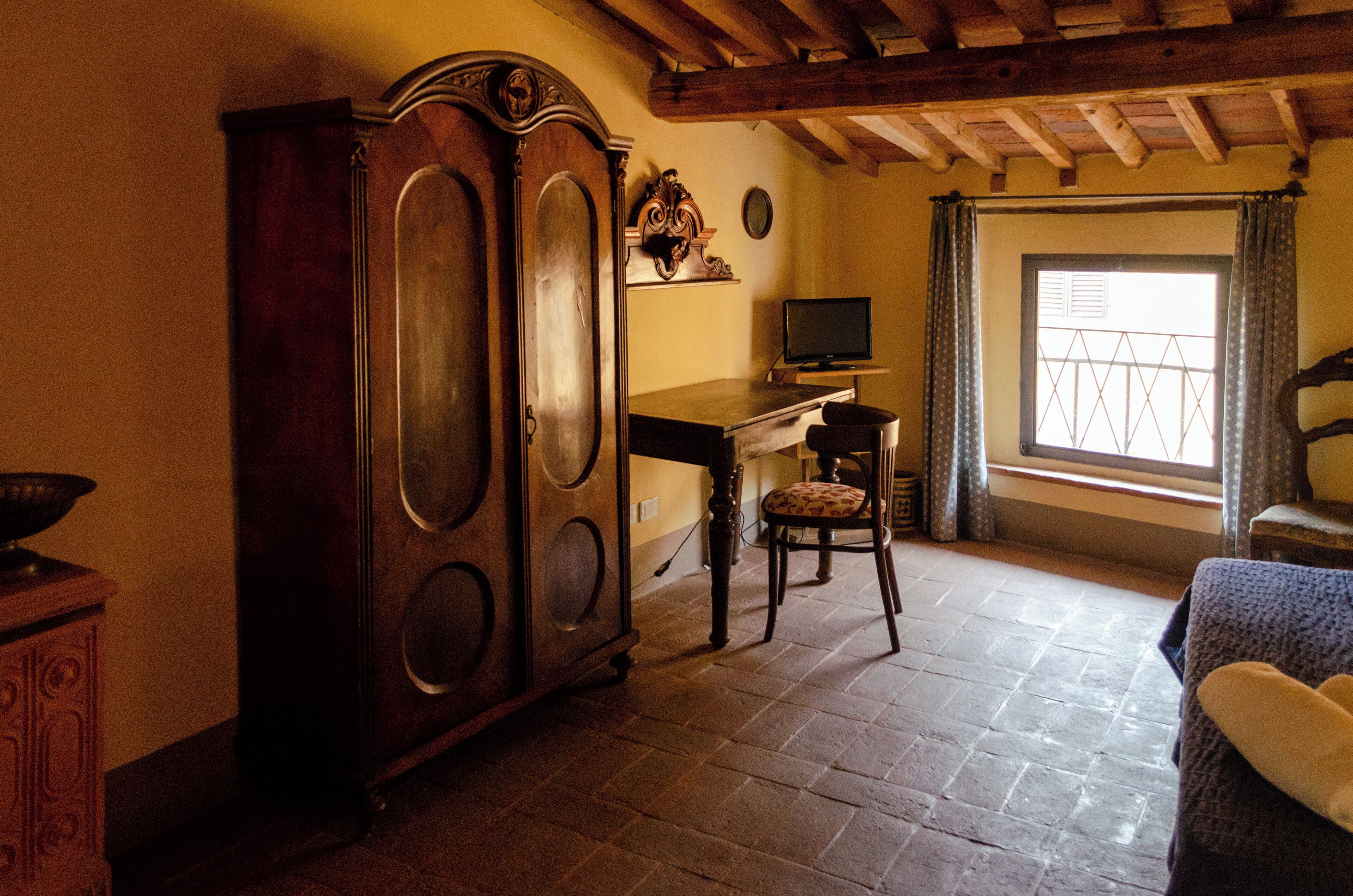 A room with a wooden desk, a chair, a television, and a large wooden cabinet.