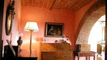 A room with a brick ceiling, a wooden dresser, a lamp, a framed painting, and a mirror.