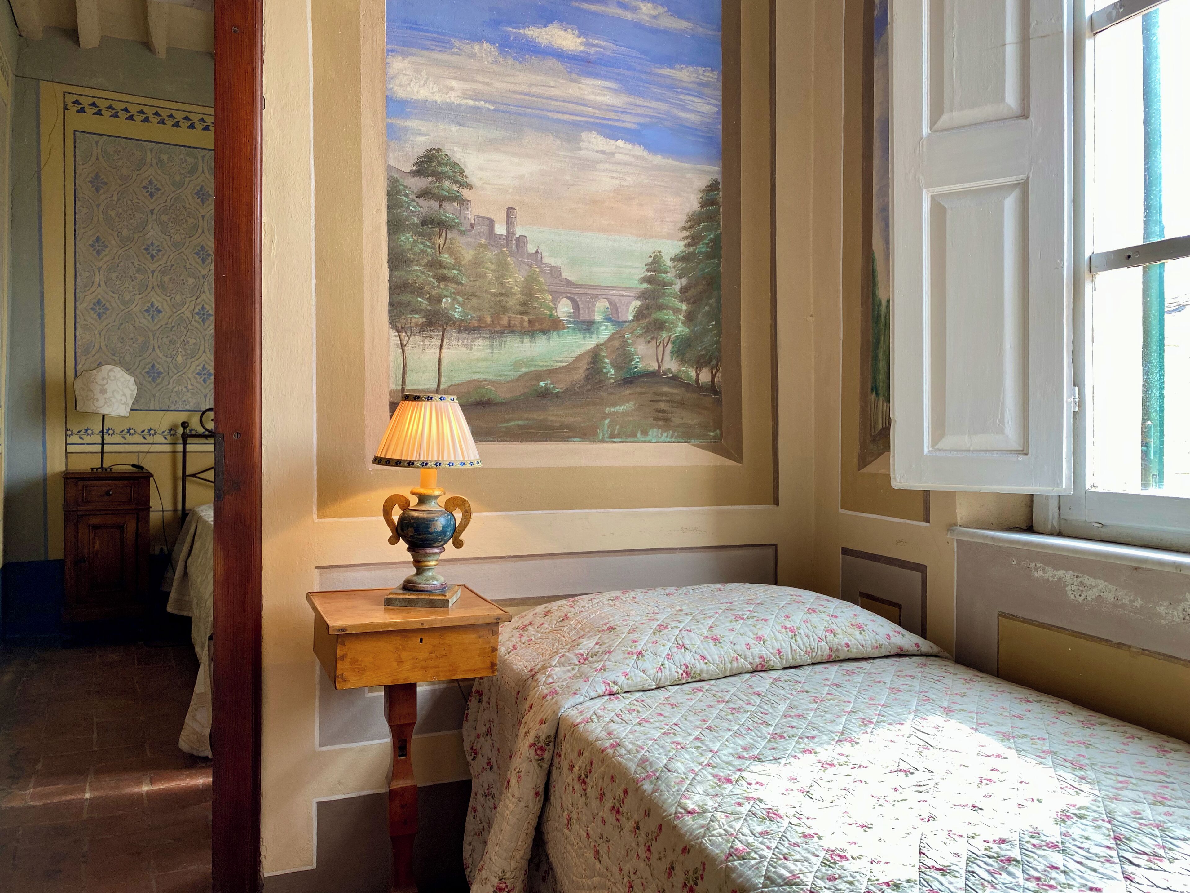 Une chambre à coucher avec un lit, une table de chevet, une lampe, un tableau au mur et une fenêtre.