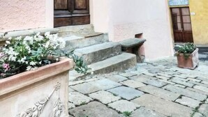 A building with a pink facade, a wooden double door, and a stone staircase leading to the entrance.