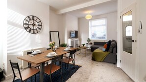 Una sala de estar moderna con una mesa de comedor de madera, un sofá y un televisor.