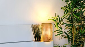 Una habitación moderna con pared blanca, una lámpara de pie y una planta en maceta.