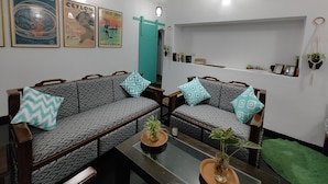A living room with two sofas, a coffee table, a clock, and wall art. - Happy hammocks, Weligama (Weligama)