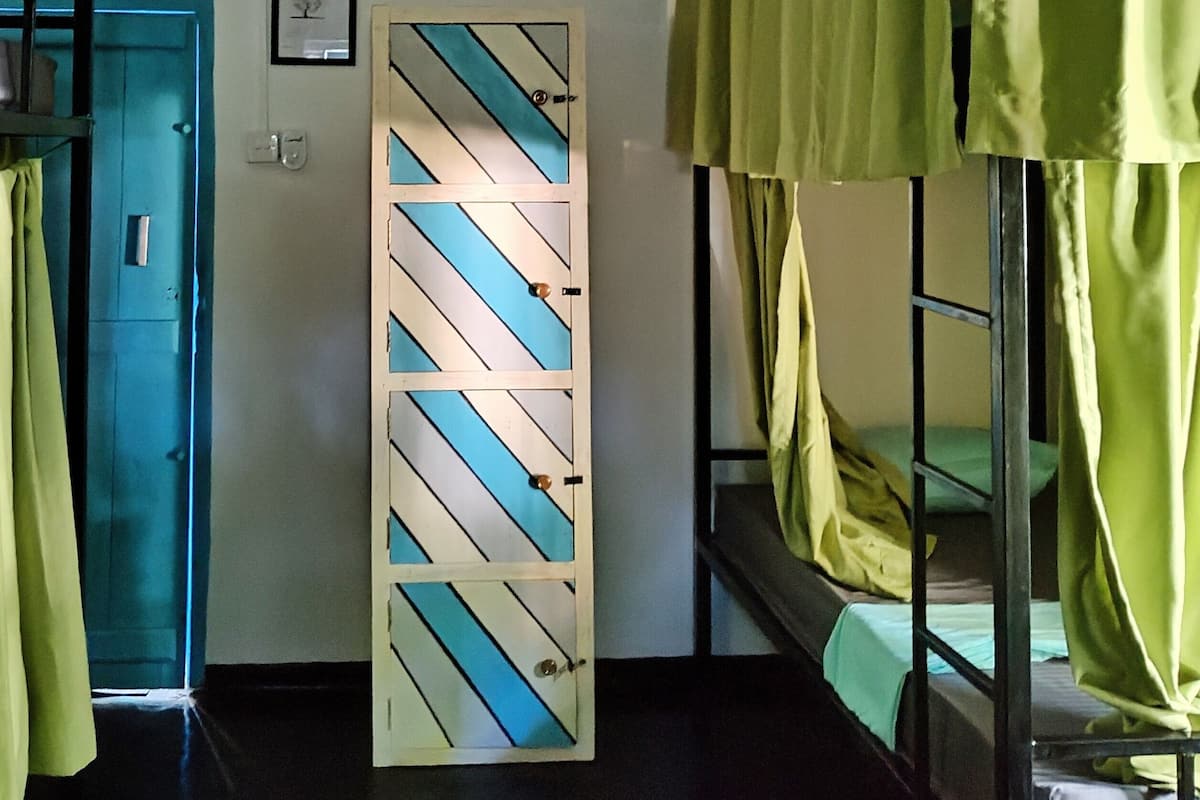 Une chambre de dortoir avec des lits superposés, une porte et un meuble fixé au mur.