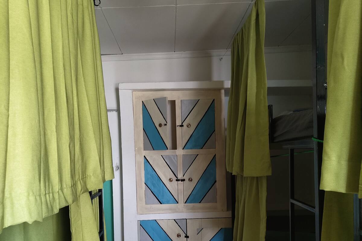 Une pièce avec un lit, une porte ornée de motifs géométriques et un ventilateur de plafond.