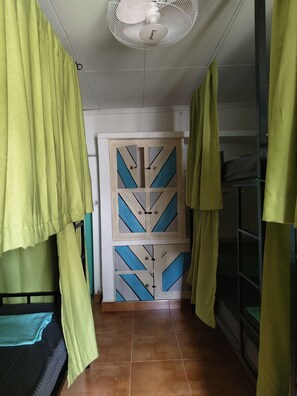 Una habitación con una cama, una puerta decorada con diseños geométricos y un ventilador de techo.