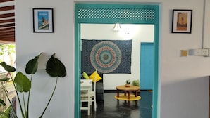 A doorway leading to a room with a patterned tapestry, a potted plant, and a small table with a plant. - Happy hammocks, Weligama (Weligama)