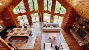 A spacious loft-style room with a high ceiling, large windows, a fireplace, and a cozy seating area.