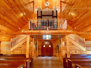 L’intérieur d’une église en bois, avec des bancs, un orgue en bois et une galerie.
