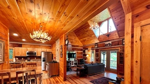 A log cabin interior with a kitchen, dining area, and living room.